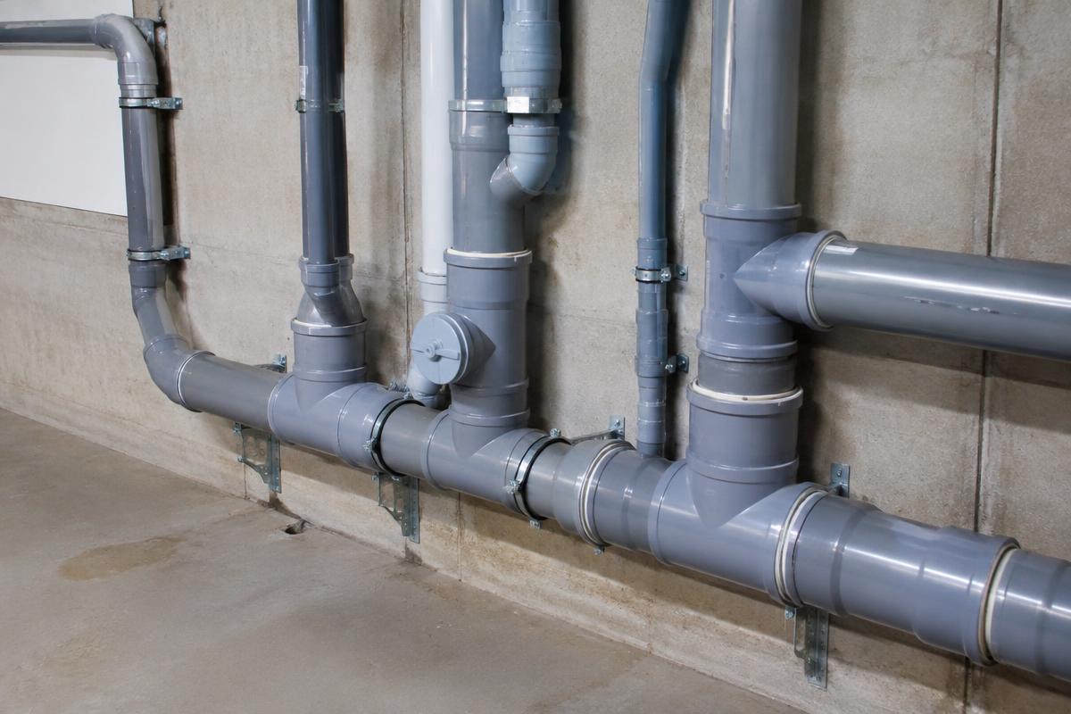 Réseau d'évacuation d'eaux usées en PVC installé dans un sous-sol